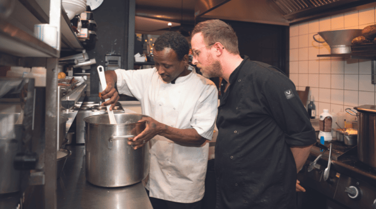 Deelnemer aan het werk in de keuken, met begeleiding chef